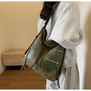 Macro shot of olive green corduroy bag with heart-shaped leather pockets and silver zippers