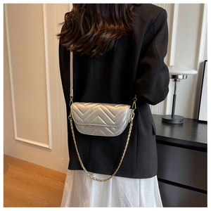 Detail of silver chevron quilted crossbody bag with gold chain strap on female model