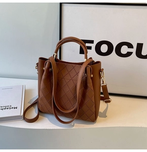 Close-up of brown bucket bag with quilted stitching and polished gold metal buckles