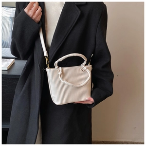 Detailed view of cream pleated bucket bag with gold hardware and removable shoulder strap