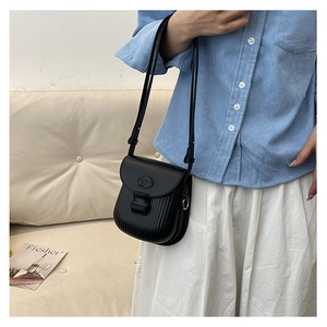 Detail of a black crossbody bag with vertical pleats and an adjustable shoulder strap