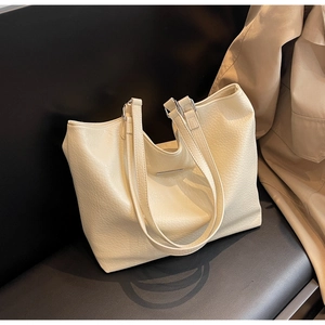 Macro detail of beige pebble grain faux leather and metallic bar on tote bag