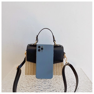Detailansicht der Mini-Strohtasche mit Lederklappe und Größenreferenz durch Smartphone