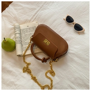 Close-up of brown leather crossbody bag with golden twist lock on white fabric
