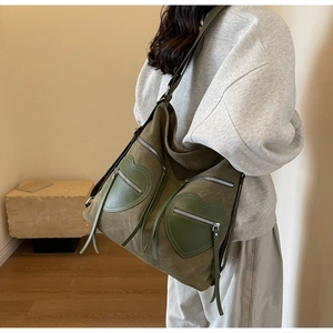 Detail of olive green corduroy tote bag with heart-shaped zipper pockets and long tassels