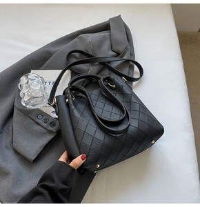 Detailed macro view of the black quilted texture and golden metal feet on the bucket bag