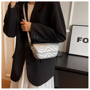 Side view of a silver quilted shoulder bag with golden hardware on a female model