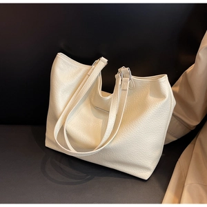 Detail of creamy white tote bag showing premium lychee grain leather texture and metal bar