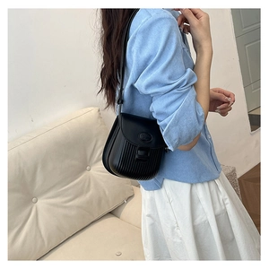 Detailed view of black textured leather crossbody bag with vertical stripes on casual model