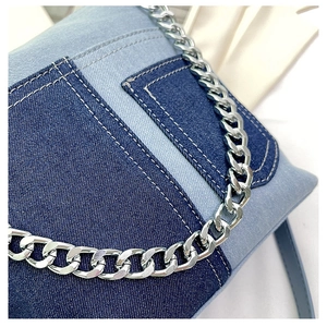 Detailed close-up of blue patchwork denim bucket bag with silver metal chain strap