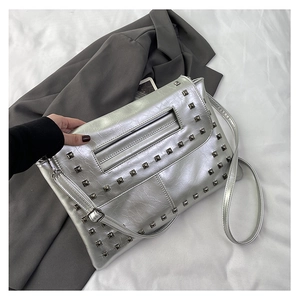 Dettaglio della borsa argento metallizzato con borchie quadrate e texture in pelle vintage