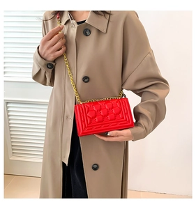 Macro shot of red quilted faux leather handbag with elegant gold metal chain strap