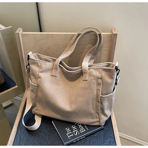 Detail view of beige corduroy tote bag showing side pockets and detachable strap