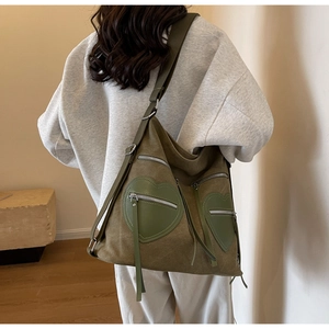 Detail view of military green canvas backpack showing heart-shaped pockets and silver zippers