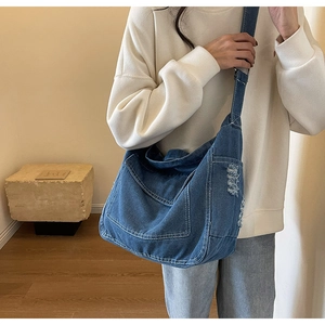 Dettaglio della borsa a tracolla in denim blu lavato con finitura usurata e cuciture