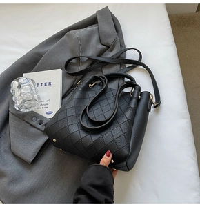 Detail of black leather bucket bag with quilted rhombus pattern and adjustable strap