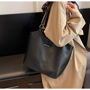 Close-up of black pebble leather tote bag with silver bar detail and minimalist design