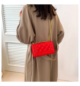 Detail of red faux leather shoulder bag with heart embossed texture and gold chain strap