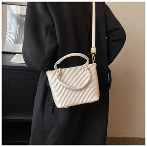 Macro detail of cream pleated bucket bag texture with gold hardware and round handle