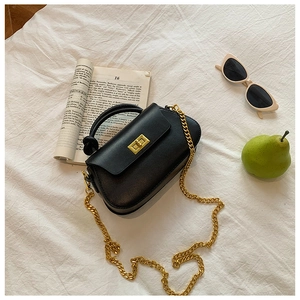 Detail shot of a black mini crossbody bag with a knotted handle and golden chain strap