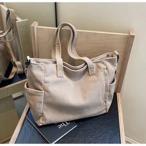 Close-up of beige corduroy tote bag showing vertical rib texture and side pockets