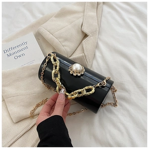 Close-up of black cylinder evening bag with pearl top handle and golden chain details