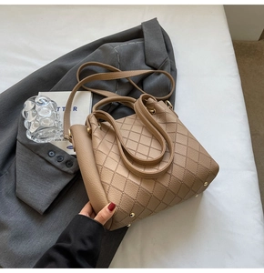 Close-up of camel leather bucket bag featuring rhombus stitching and gold metal feet