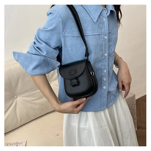 Detailed side view of black crossbody bag with vertical textured stripes and metal logo