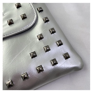 Dettaglio della borsa a busta argento con borchie quadrate e texture in pelle pieghettata