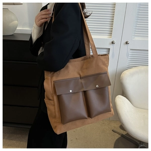 Detail of canvas tote bag with contrast faux leather pockets and metal snaps in a casual style