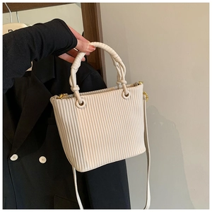Close-up of vertical pleated texture and braided handle on cream white bucket bag