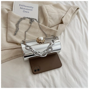Macro view of silver mirror cylinder bag with pearl clasp and metal chain strap