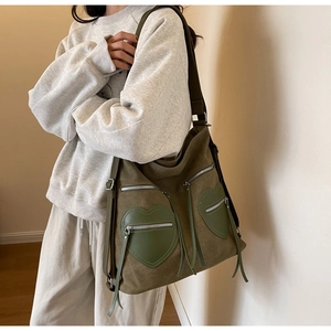 Detail of olive green corduroy backpack with heart-shaped pockets and fringe zippers