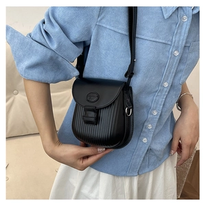 Close-up of black crossbody bag with vertical stripe texture worn by model in light blue shirt