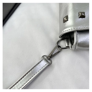 Dettaglio della borsa in pelle argento con gancio metallico e rivetti quadrati