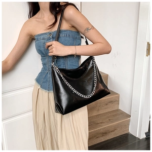 Close-up of black soft leather tote bag with stylish silver chain detail on stairs