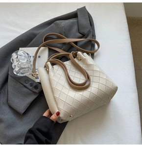 Close-up of cream quilted bucket bag with contrast brown handle and drawstring closure