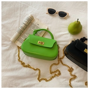 Detail of mini leather bags with knotted handles and gold chain straps in green and black
