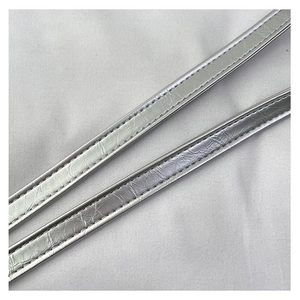 Dettaglio di tracolle argentate metallizzate con cuciture bianche e finitura a pieghe