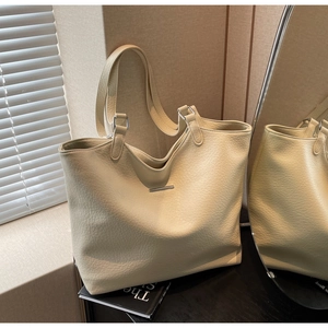 Detailed macro view of the beige pebble texture leather and silver buckle on this tote bag