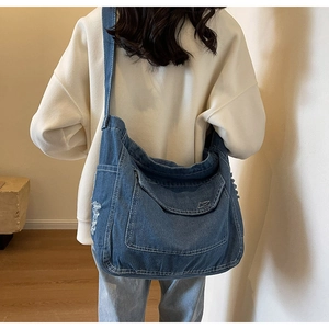 Dettaglio della borsa a tracolla in denim con bordi sfrangiati e tasca con patta sul modello