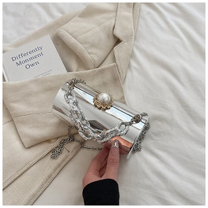 Detailed view of silver mirror cylindrical evening bag with large pearl clasp and chain straps
