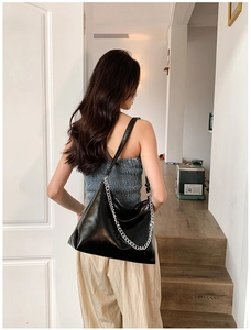 Detail of soft black leather tote bag with thick silver chain and wide shoulder strap