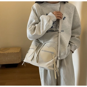 Detailed close-up of cream canvas shoulder bag with heart leather pockets and tassels