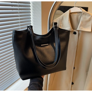 Close-up of black lychee grain tote bag with sleek metal detail and soft leather texture