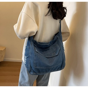 Dettaglio della borsa a tracolla in denim con lavaggio retrò e bordi con frange usurati