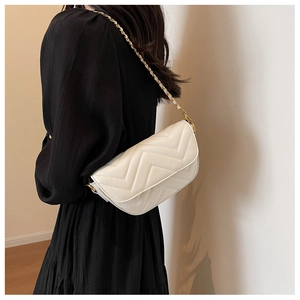 Detail of cream quilted leather shoulder bag with gold chain strap on female model