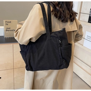 Detail of black corduroy tote bag showing large capacity, side pockets and ribbed texture
