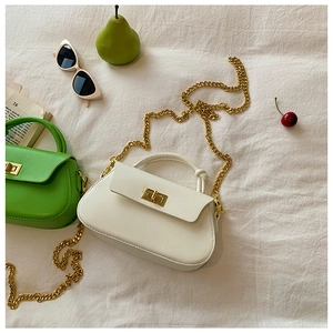 Close-up of white and green mini chain bags with gold hardware on aesthetic background