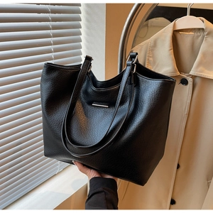 Close-up of black lychee grain tote bag with elegant metal strip and dual shoulder straps